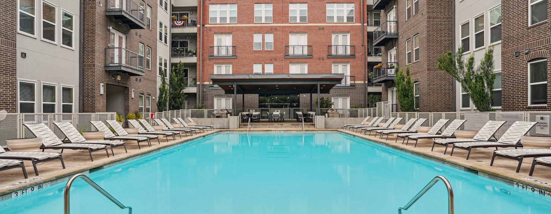 pool with many lounge chairs and a multi story building in the background